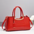 Chic red patent leather Boston bag with crocodile texture and gold hardware details - Red