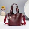 Detail of burgundy leather tote with gold logo and stylish red-white striped strap - Red