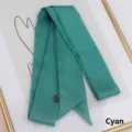 Detailed close-up of a long cyan satin silk scarf with sharp corner tips and wash label - 200cm / Aqua Blue