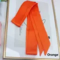 Close-up of long orange satin ribbon scarf with a silky finish on a decorative background - 200cm / Orange