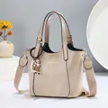 Detail of beige faux leather tote featuring gold lettering and cute doll charm with pearls - Khaki
