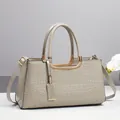 Détail du sac Boston en cuir verni gris à motif crocodile avec garniture dorée chic - Gris