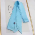Macro detail of sky blue satin ribbon scarf with textile care label and 100% polyester tag - 200cm / Sky Blue