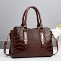 Détails d'un sac à main marron foncé à motif crocodile avec boucles dorées élégantes - café
