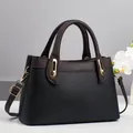 Schwarze Handtasche mit Litschi-Struktur, braunen Griffen und goldener Hardware - Schwarz