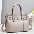 Detail shot of beige lychee texture faux leather bag with silver metal swivel lock clasp - Gray