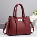 Detail of burgundy lychee pattern leather handbag featuring a silver twist lock and strap - Red