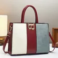 Gros plan détaillé d'un sac à main en cuir tricolore avec boucle dorée en forme de B - Rouge