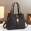 Detail of a brown woven texture bucket bag with gold hardware and dual handles - Coffee