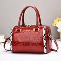 Sac Boston rouge avec texture crocodile, finitions serpent et accessoires dorés - Bordeaux