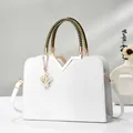 White crocodile pattern handbag with woven handle and elegant pearl charm on minimalist background - White