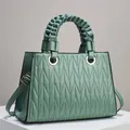 Detail van saliegroene gewatteerde handtas met gevlochten handvat en gouden ringen - L30cm B11cm H21cm / Groen