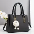 Elegante borsa a mano nera in trama intrecciata con dettagli dorati e ciondolo - Nero