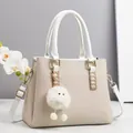 Dettaglio borsa beige intrecciata con manici in pelle bianca e ciondolo a pompon morbido - Bianco Sporco