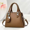 Elegant brown leather bucket bag with silver heart charm and crossbody strap - Khaki