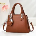 Brown litchi grain bucket bag with silver heart charm and crossbody strap shown in a 45-degree view - Earthy Yellow