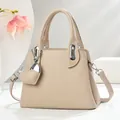 Detail of lychee pattern leather handbag with silver hardware and heart pendant charm - Apricot