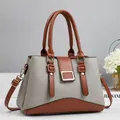 Detail view of contrast stitching and gold buckle on gray and brown leather handbag - Gray