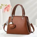 Brown litchi leather handbag with heart charm and shoulder strap shown in side view - Earthy Yellow