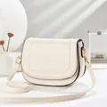 Cream white saddle bag with black trim and golden hardware in a minimalist setting - Off White
