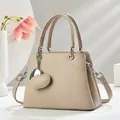 Macro shot of apricot tote bag featuring lychee texture and silver heart charm detail - Light Khaki