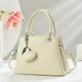 Detail of beige crossbody bag with lychee texture leather and heart pendant - Off White