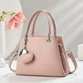 Detailansicht der rosa Handtasche mit Litschi-Muster und Herz-Anhänger - Rosa