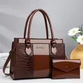 Dettaglio della borsa marrone scuro con motivo a coccodrillo, finitura lucida e logo - 31x13x23cm / Marrone
