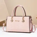Rosa Damen-Handtasche mit Schlangenprägung, goldenen Beschlägen und praktischem Tragegriff - Rosa