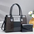 Close-up of grey crocodile-embossed handbag set with polished finish and metal logo - 31x13x23cm / Gray