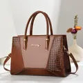 Detail of brown glossy patent leather with crocodile texture on a large tote bag - Earthy Yellow