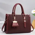 Elegant wine red textured leather handbag for women featuring top handles and a shoulder strap - 33x12x23cm / Red