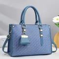 Detailaufnahme der blauen Tasche mit geometrischem Muster, Ledergriffen und Goldbeschlägen - 33x12x23cm / Blau