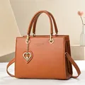 Détail du sac à main marron en cuir avec marquage doré et pendentif cœur en perle - Jaune Terre