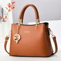 Détail du sac à main en cuir PU caramel avec lettrage doré et breloque élégante - Jaune Terre