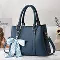 Detail of navy blue pebble leather handbag with checkered bow scarf and metal hardware - Blue