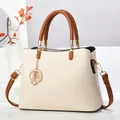 Détail du sac cabas beige avec anses marron et accessoire de breloque étoile et lune dorée - Blanc Cassé