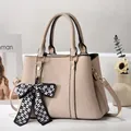 Detail of beige lychee textured handbag with a checkered bow charm and golden hardware - Off-white