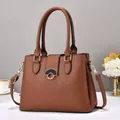 Elegant brown pebbled leather handbag with gold hardware and stylish clasp on desk - Earthy Yellow