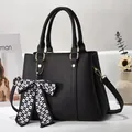 Detail of black pebbled faux leather handbag with a checkered bow and gold metal hardware - Black