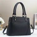 Close-up of black lychee grain texture and gold hardware on a chic women handbag - Black