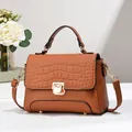 Détail du sac marron avec texture crocodile, fermoir doré rotatif et picots de protection - Jaune Terre