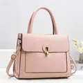 Vue détaillée du sac à main rose en cuir texturé avec fermoir rotatif et bandoulière - Rose