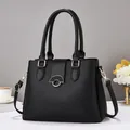 Elegant black lychee grain leather handbag with gold metal clasp and adjustable shoulder strap - Black