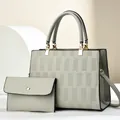 Graue Handtasche aus geprägtem Kunstleder mit passender Clutch und goldenen Metallteilen - Handtaschen- und Clutch-Set / Grau