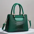 Detailed macro view of the glossy emerald crocodile texture and gold hardware on bag - Green