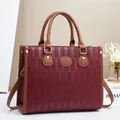 Dettaglio della trama bordeaux e finiture in pelle marrone con fibbia dorata sulla borsa - L32 P12 A25 / Borgogna
