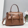 Detailed view of retro messenger bag with oil wax leather texture and silver buckles - Coffee