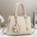 Détail du sac à main en texture tissée avec fermoir argenté et breloque fleur en cuir - Abricot