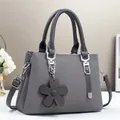 Détail du sac à main gris foncé texturé avec pendentif fleur marron et finitions argentées - Gris